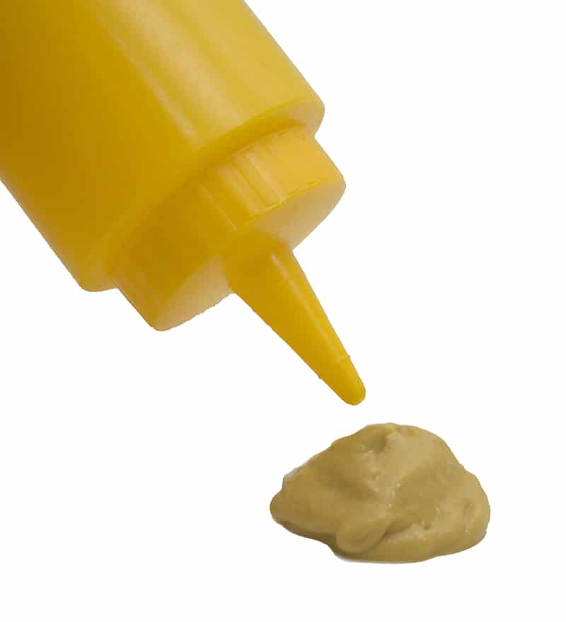 Close up of mustard coming out of a bottle.