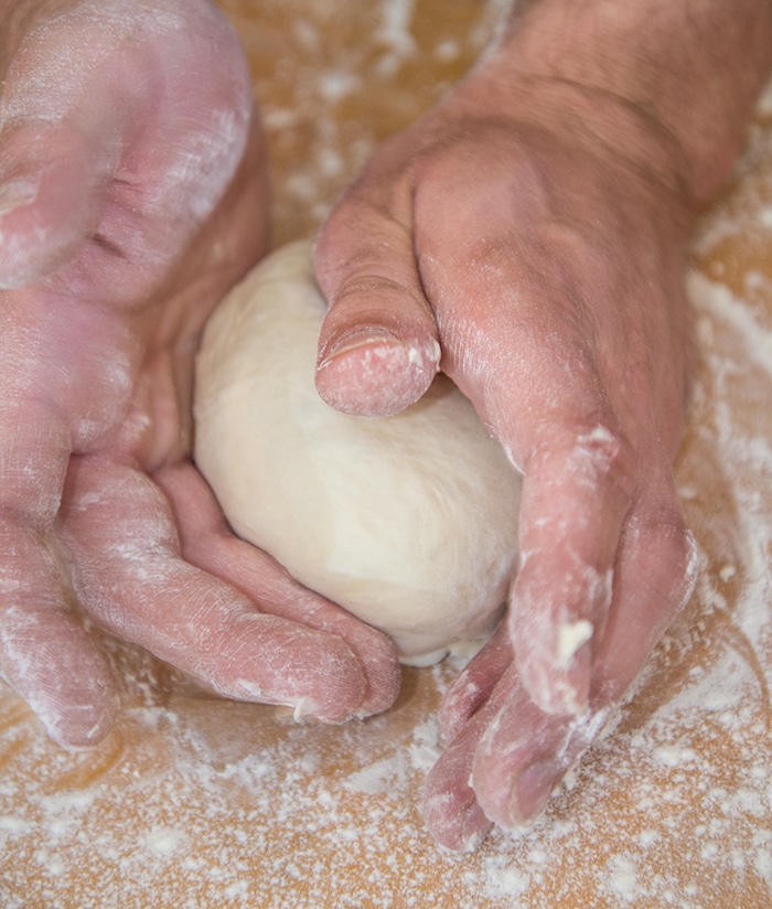 Close up of hands kneading pizza dough.