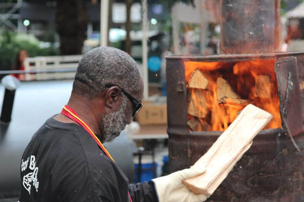 man burning wood in a burn barrel.