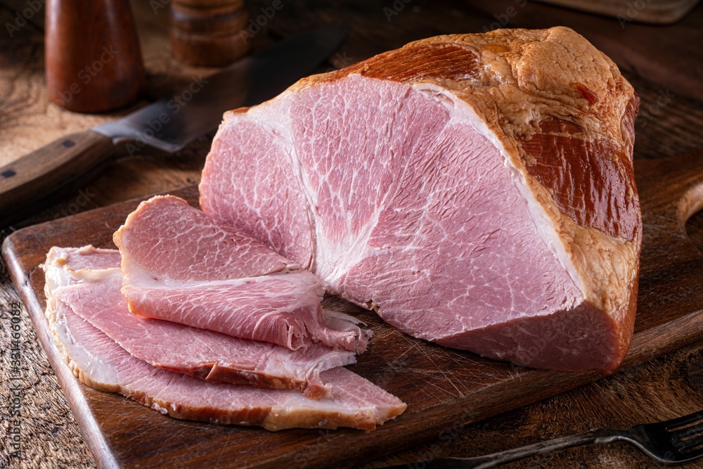 cured and smoked ham sliced on a cutting board.