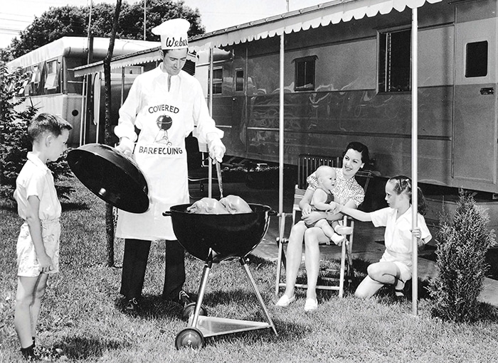 Person using an early Weber kettle grill.