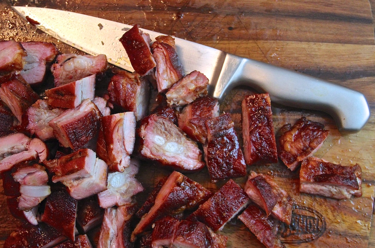 chopped smoked pork tips and a knife on a cutting board.