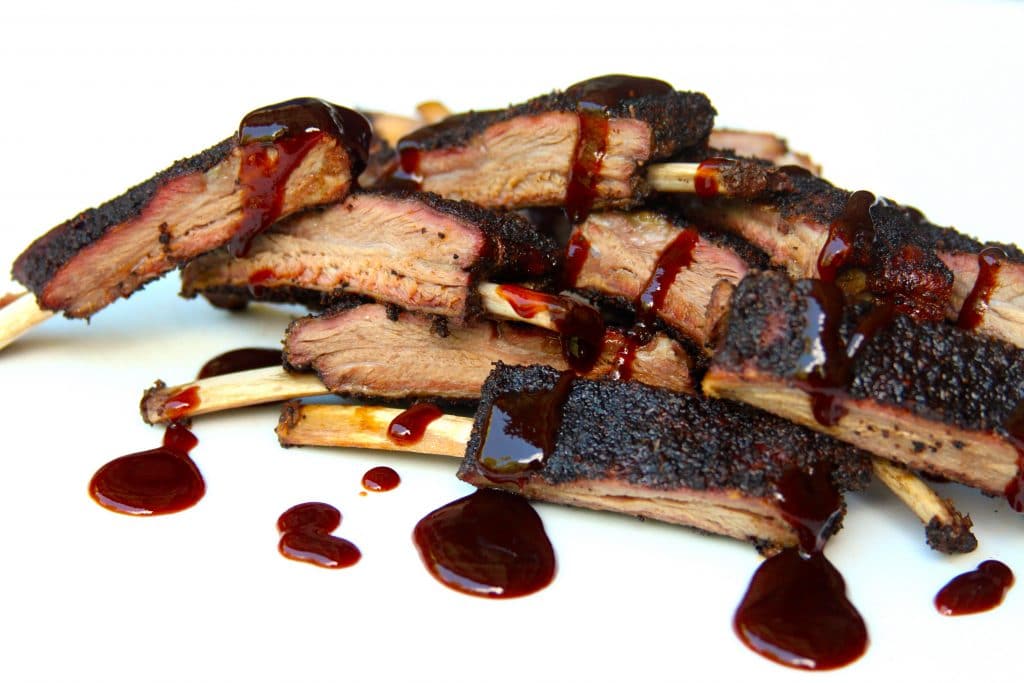 Smoked venison ribs sliced and drizzled with sauce