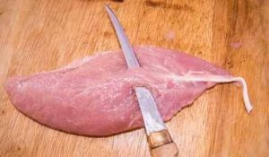 Removing the tendon from the turkey tenderloin with a filet knife