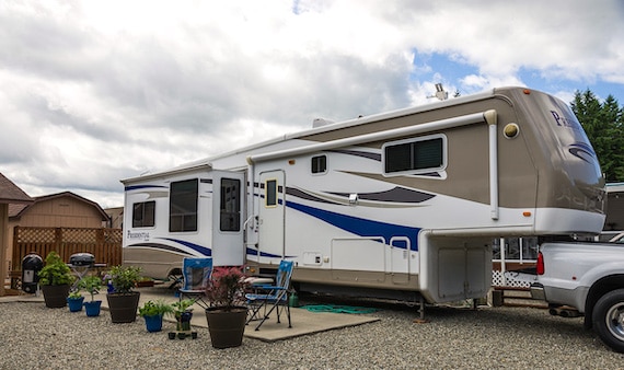 RV trailer setup with grill, smoker, and chairs