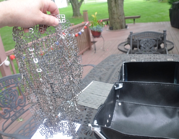 A hand hold a shiny, chain mail like net.