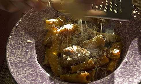 grating parmesan over pasta