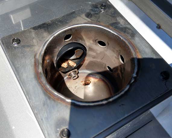 Round steel cup attached to a tube filled with wood pellets.