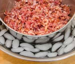 ground meat and fat in a bowl inside a bowl of ice water