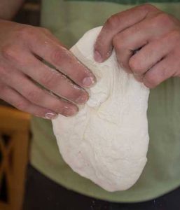 shaping pizza dough holding dough in the air