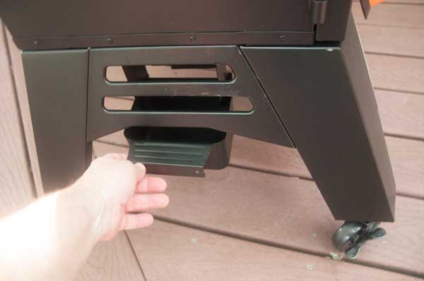 A hand pulling out a black tray from under a black cabinet
