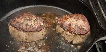 meat searing in a cast iron pan on a gas grill