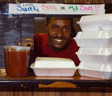 man serving boxed food through a diner kitchen window