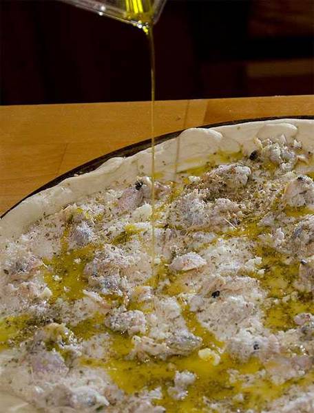 drizzling oil on pepe's white clam pizza