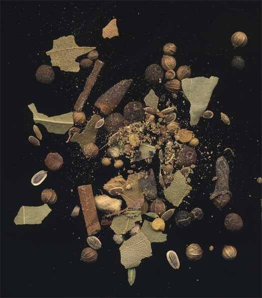 pickling spices including cinnamon sticks and bay leaves, on a black background
