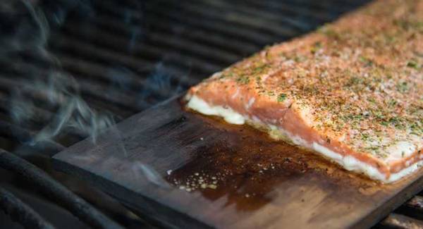 fish cooking on wooden plank