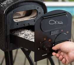 A hand on the right pulls a black metal tray from a black opening. The tray is full of ashes.