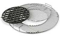 Round shiny steel rod charcoal kettle cooking grate. The center has a round removable grate section which is pulled slightly out. A heavy black metal round grate of the same size is placed next to the round center opening. 