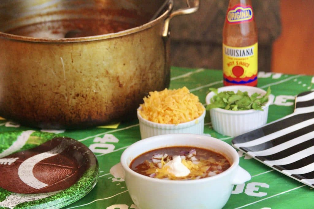 Beef chili in a bowl with chopped onions, cheese, and sour cream