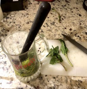 glass with muddler used for making a mojito cocktail.