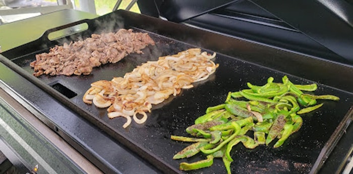 Cheesesteak ingredients cooking on a Flatrock griddle.