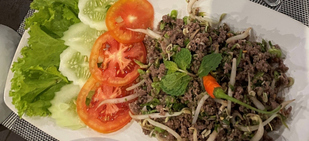 Grilled laap on a plate with tomatoes.
