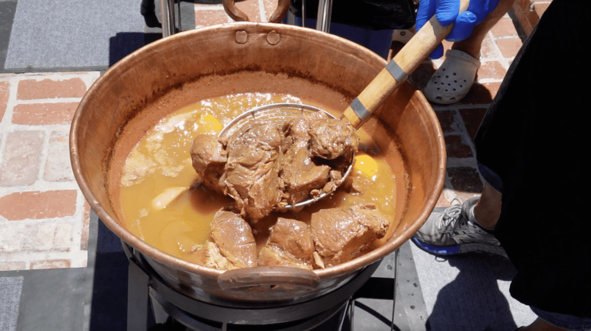 pork cubes simmering in a copper pot.