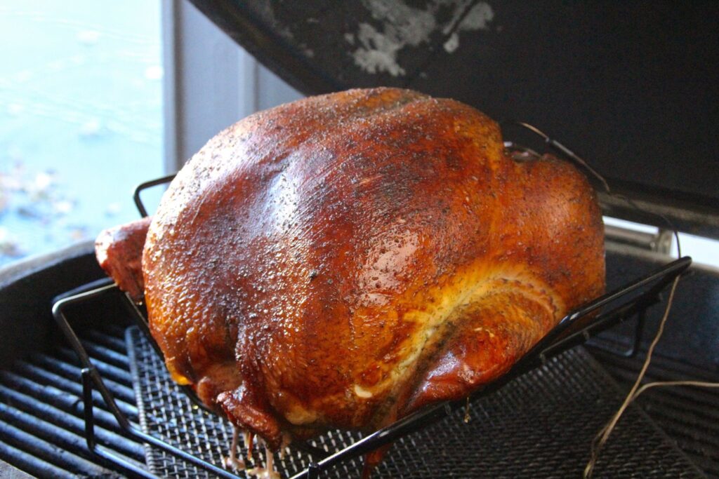 Closeup of whole smoked turkey on grill.
