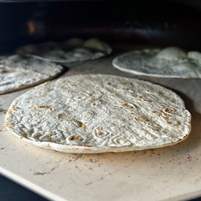 Pan of tortillas entering the pizza oven