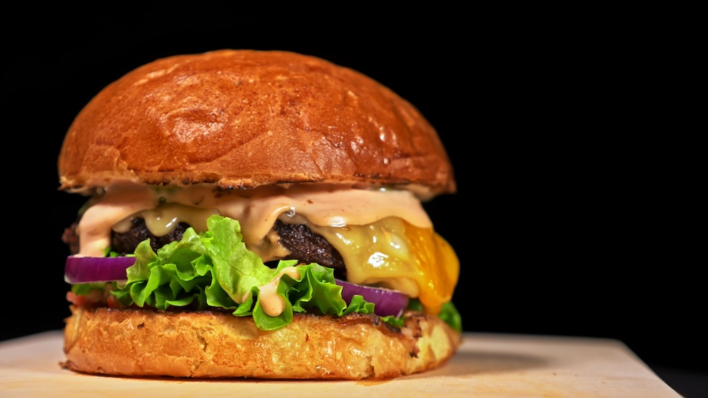 Burger with Big Mac Sauce and lettuce on bun on wooden board.