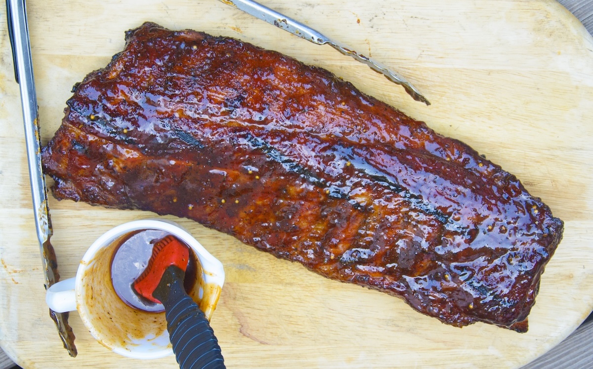 rack of ribs and sauce on a cutting board.